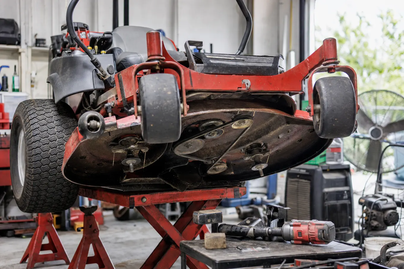 Zero turn mower in a Port Charlotte repair bay with the deck removed for spindle service